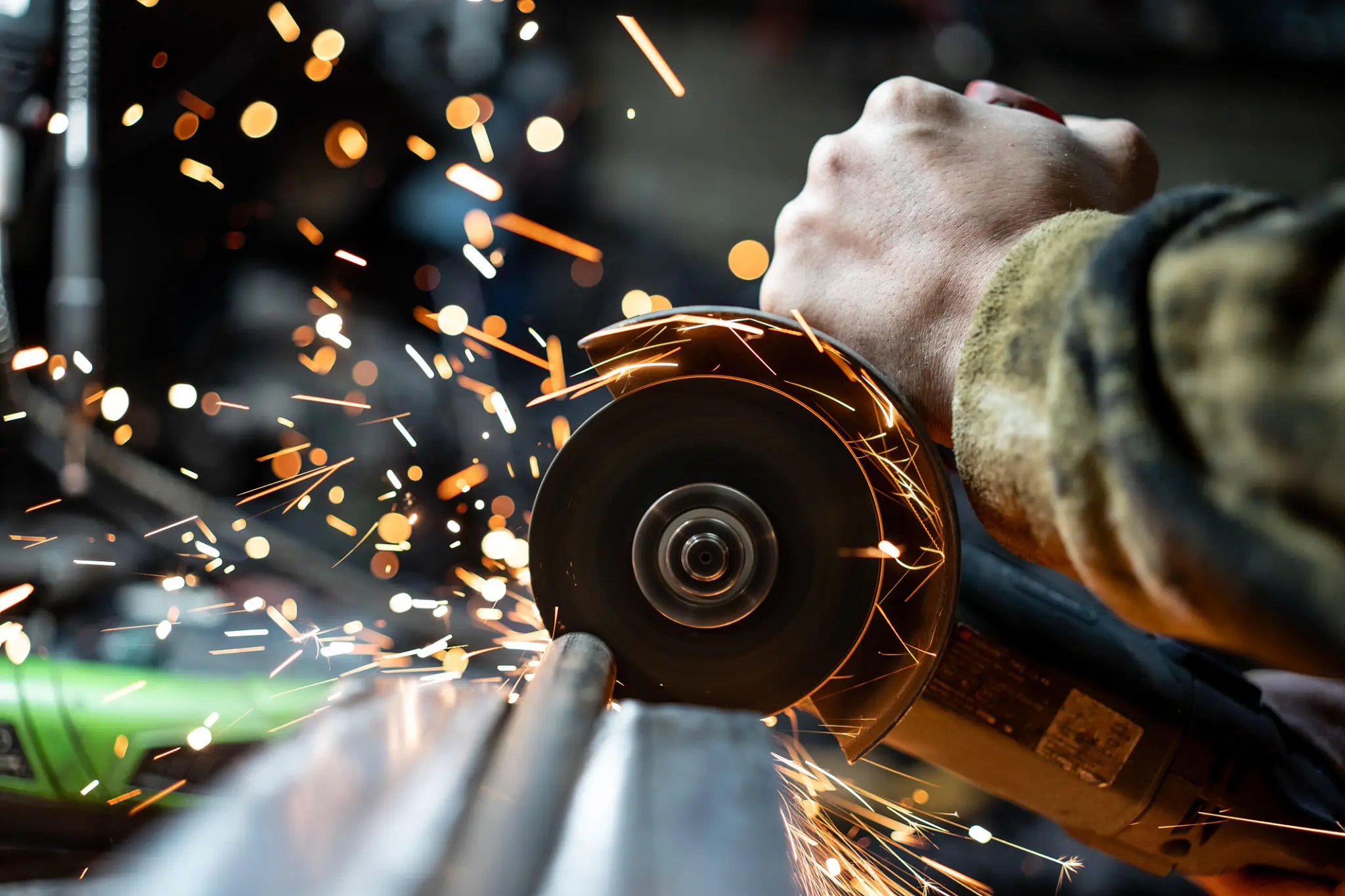 Close-up of a worker using an angle grinder with sparks flying.