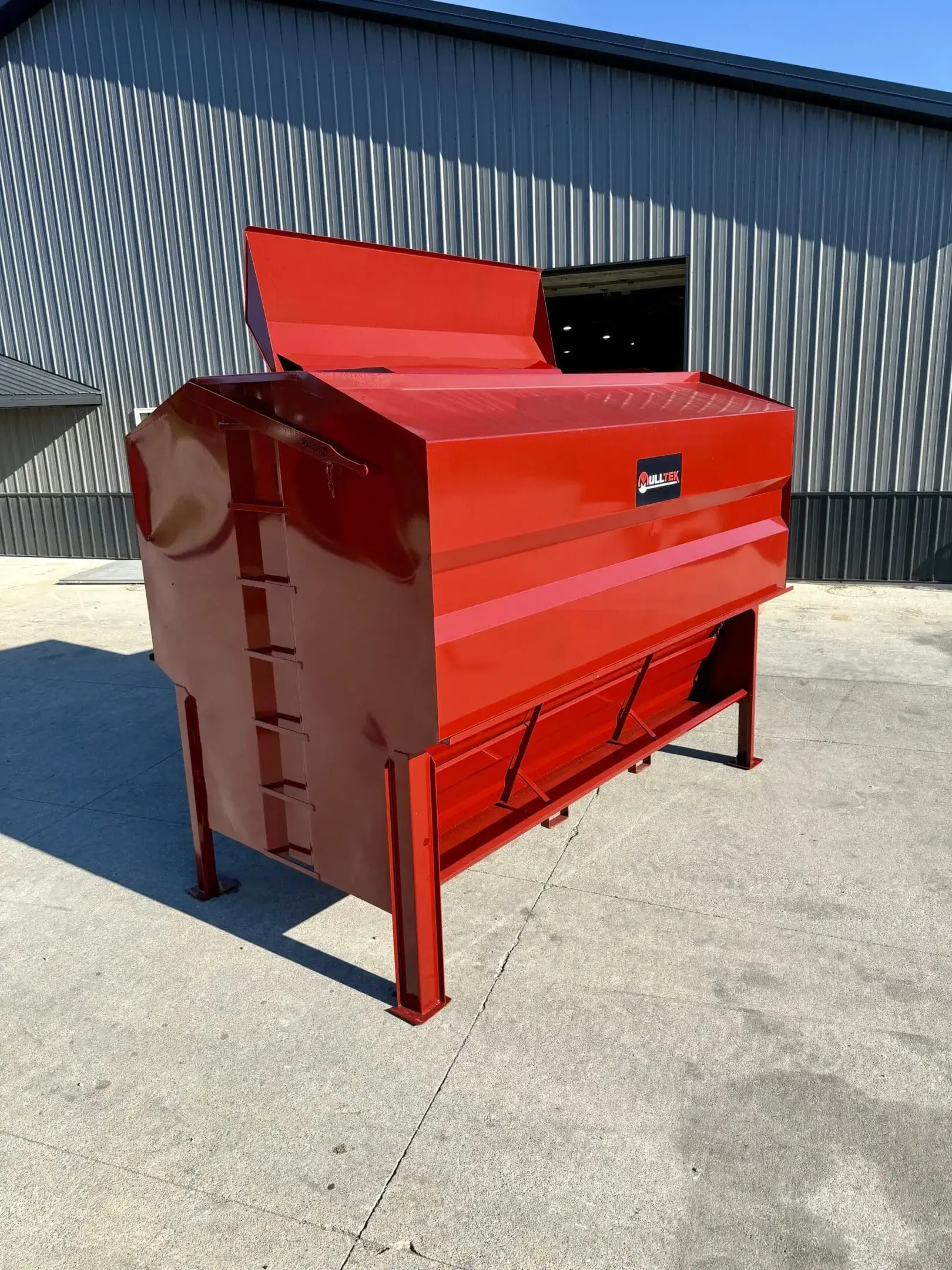 Red industrial machine outdoors on a concrete surface.